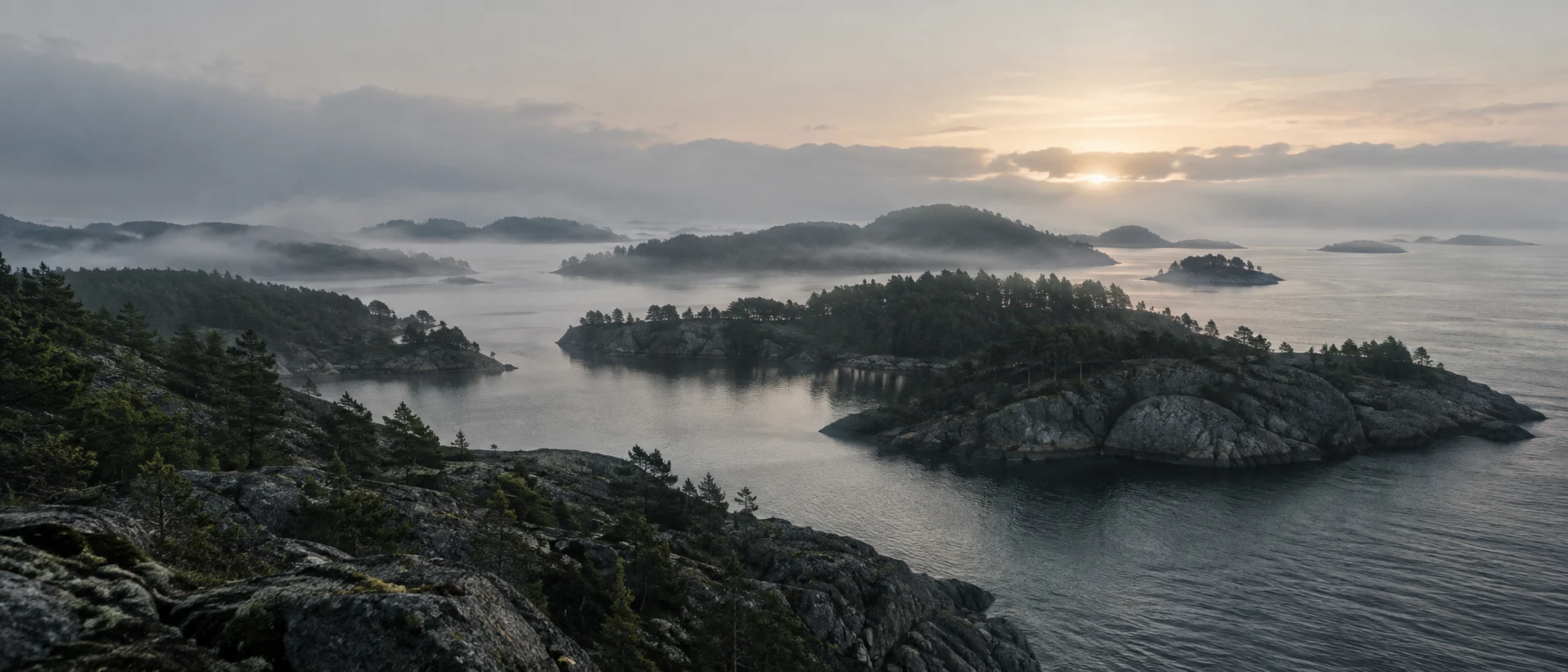 Misty forested islands opening onto a calm Nordic sea
